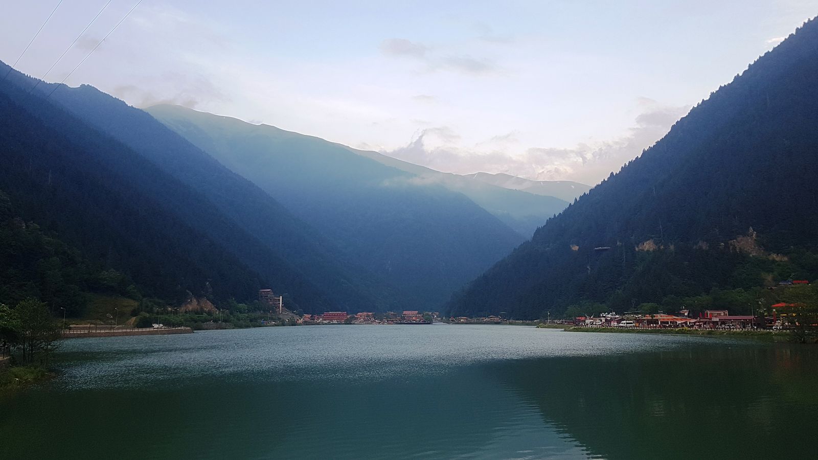 The still water of Uzungöl held between two forested slopes, with the range rising behind.