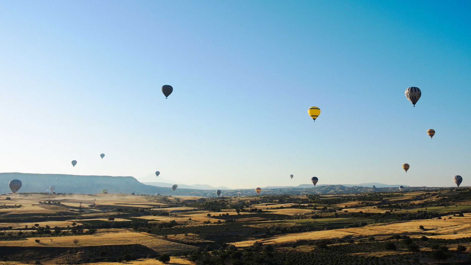 Hot-air balloons rising above the valleys of Cappadocia in the morning.