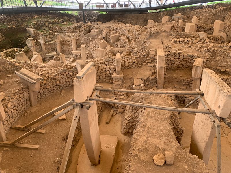 Circular stone enclosures and T-shaped pillars beneath the protective roof at Göbeklitepe.