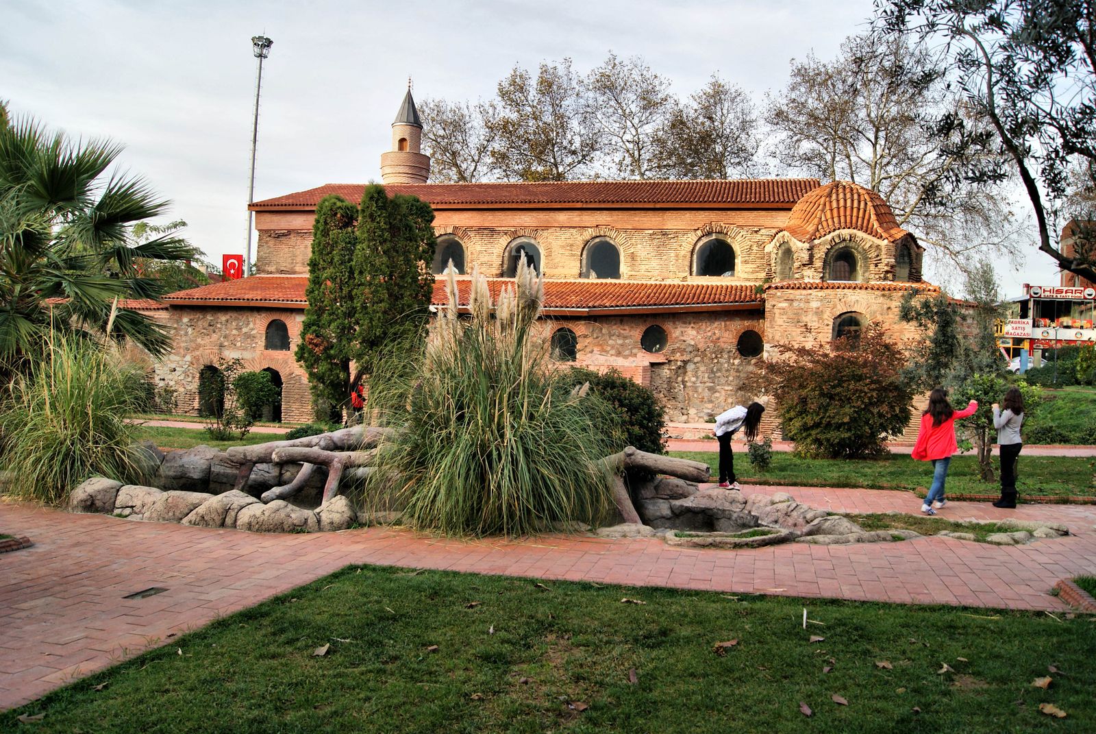 The red-brick Hagia Sophia of İznik seen beyond trees and landscaped gardens.