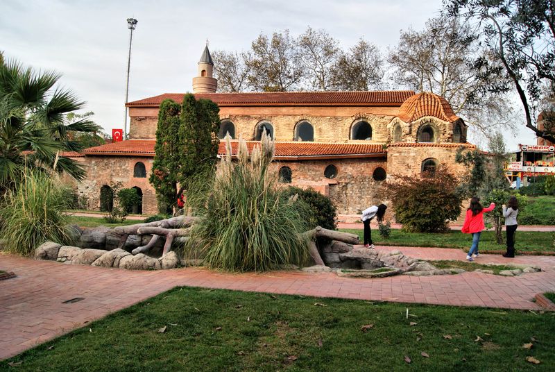 The red-brick Hagia Sophia of İznik seen beyond trees and landscaped gardens.